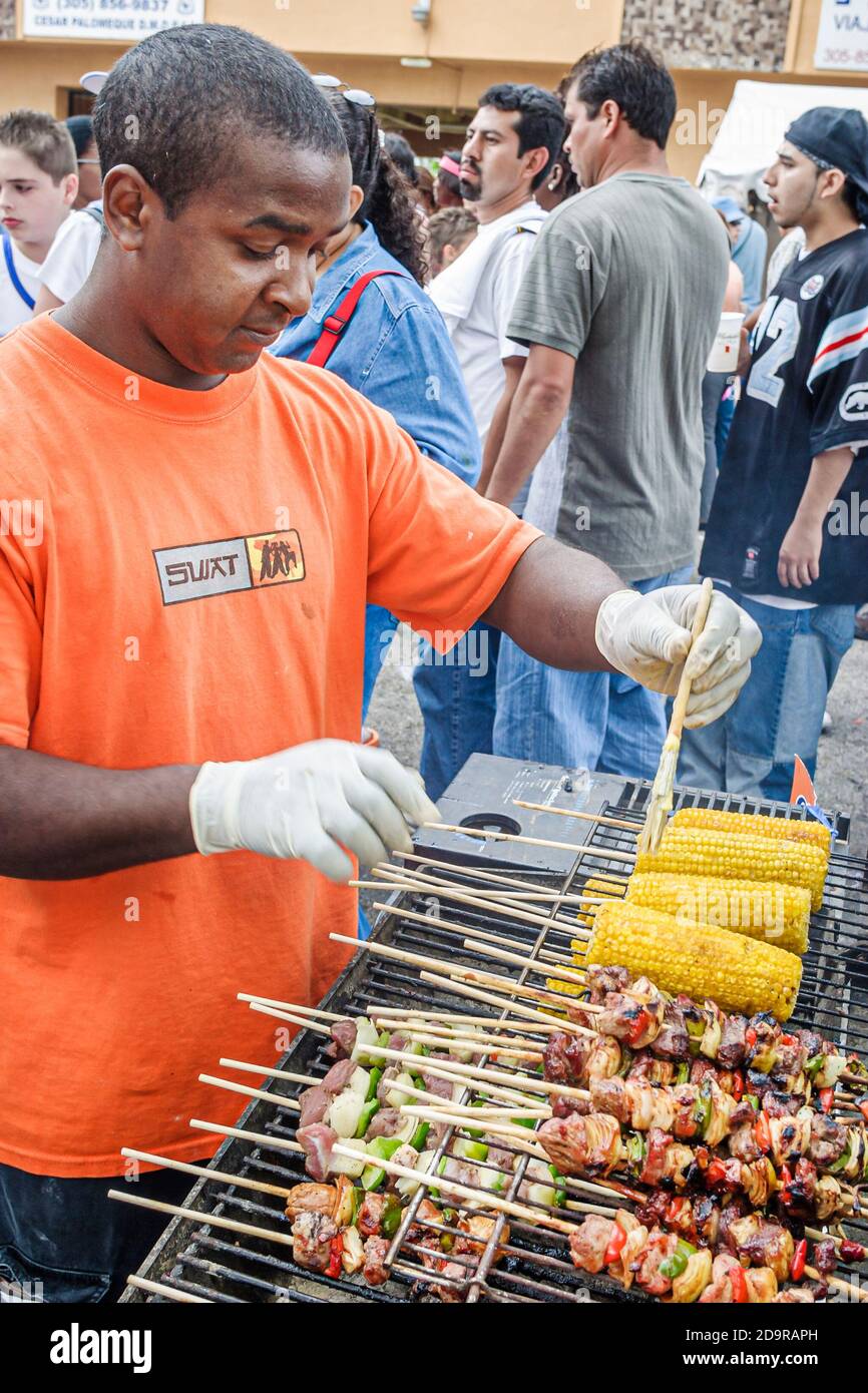Miami Florida,Little Havana,Calle Ocho Festival,evento annuale ispano immigrato stallo alimentare venditore uomo cucina, mais pannocchia carne shish kebab, Foto Stock