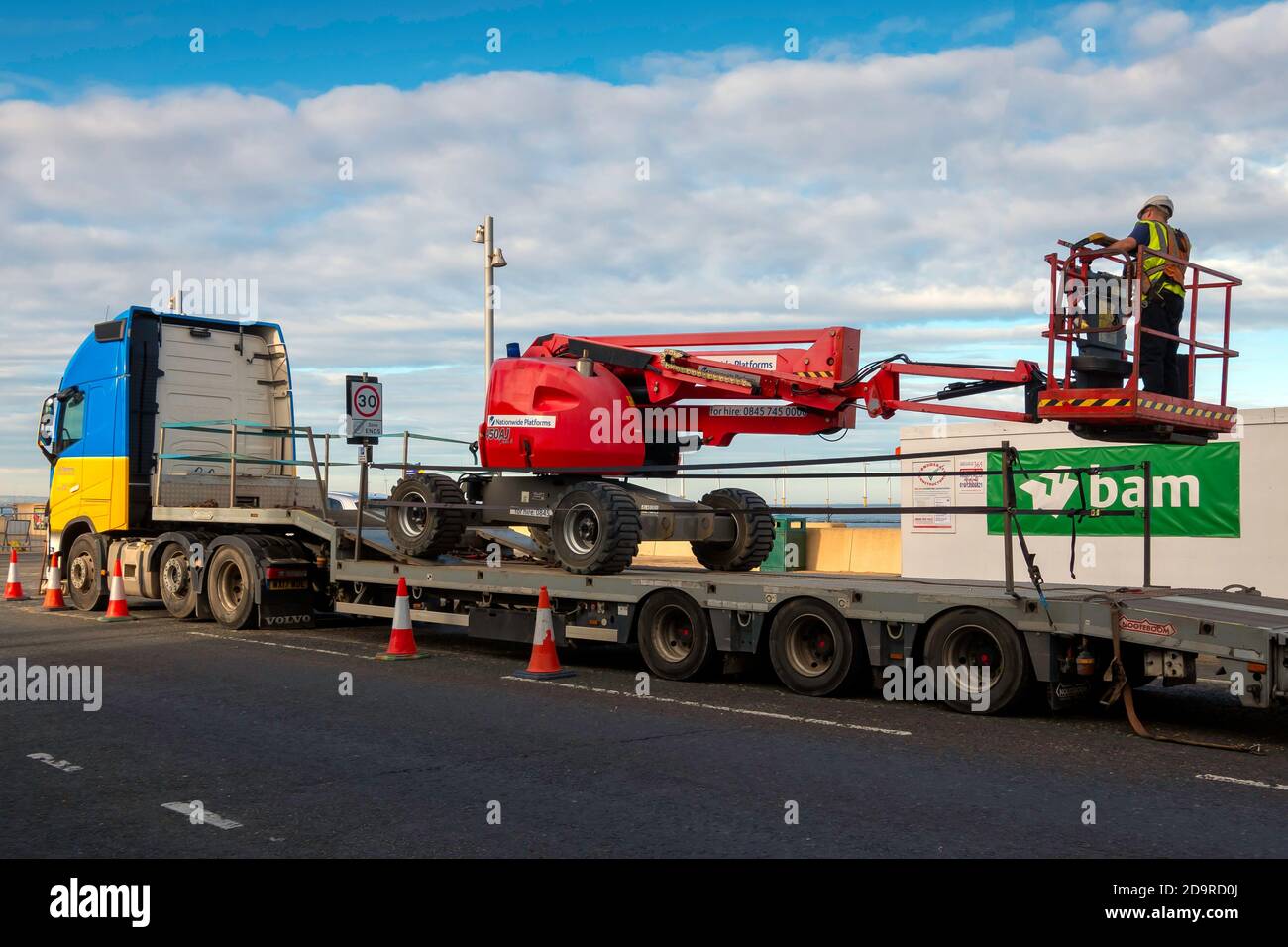 Una piattaforma idraulica portatile che viene caricata su un veicolo per il trasporto su strada quando non è più necessaria in un cantiere. Foto Stock