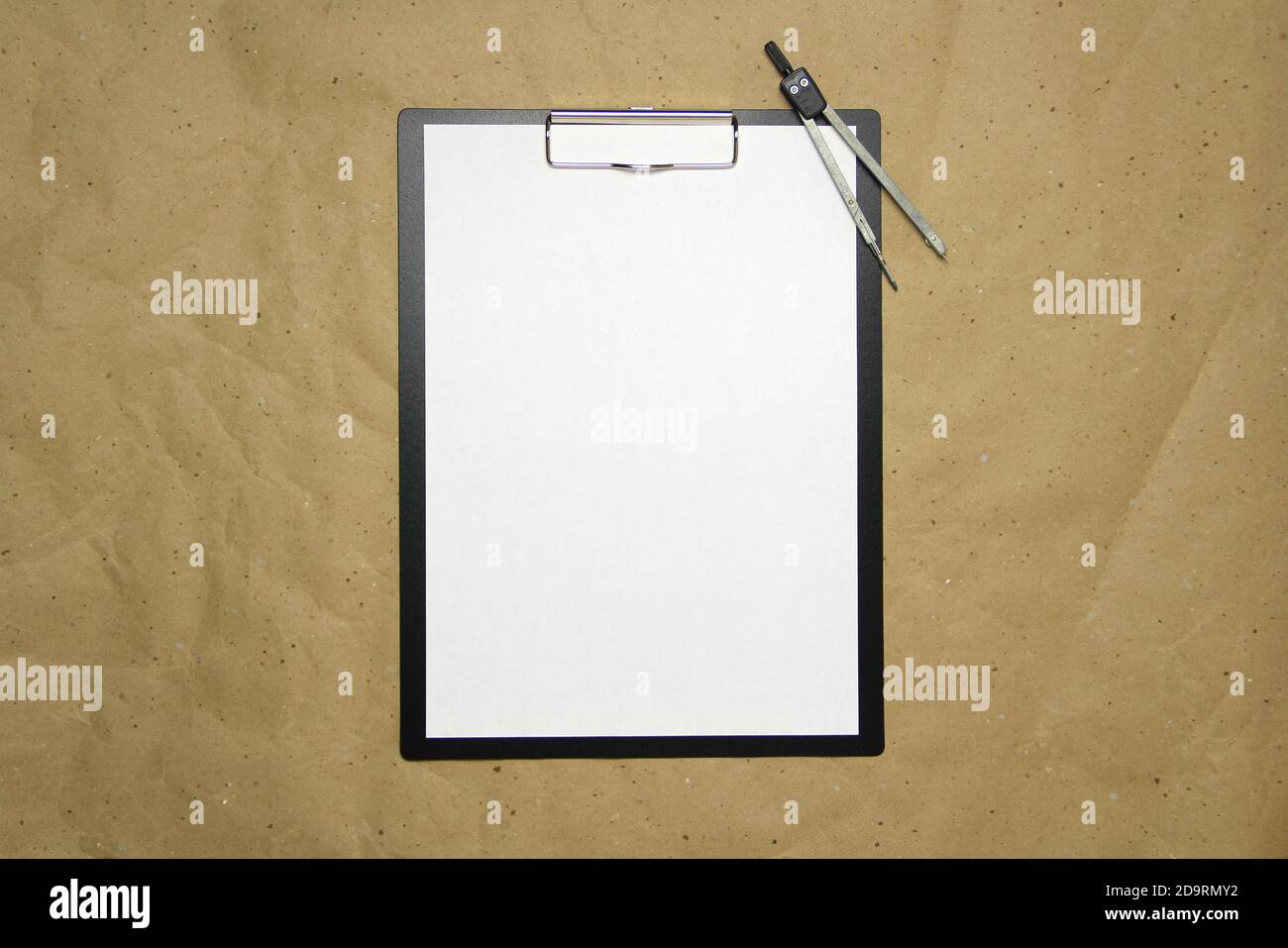 Una tavoletta con un foglio bianco di formato A4 con divisori su una carta da artigianato beige. Concetto di misurazioni, studi e costruzioni accurate. Foto di scorta con spazio vuoto per il testo e il disegno. Foto Stock