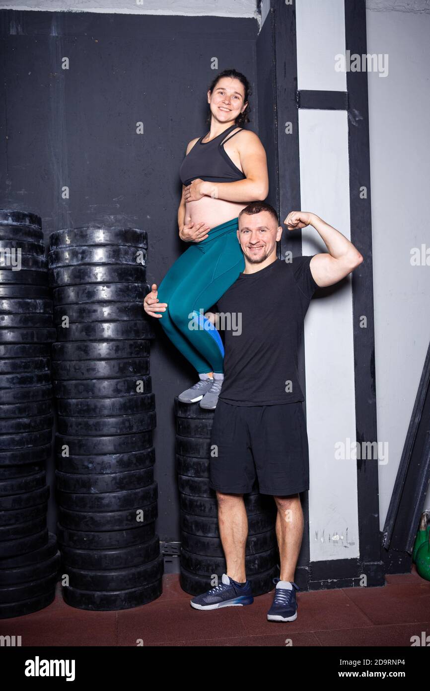 Periodo di gravidanza in donne forti muscolari atletiche. Allenamenti congiunti ed esercizi della coppia durante la gravidanza in palestra. Uomo e donna incinta Foto Stock