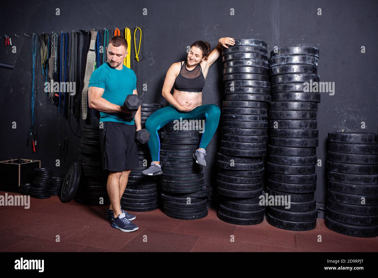 Periodo di gravidanza in donne forti muscolari atletiche. Allenamenti congiunti ed esercizi della coppia durante la gravidanza in palestra. Uomo e donna incinta Foto Stock