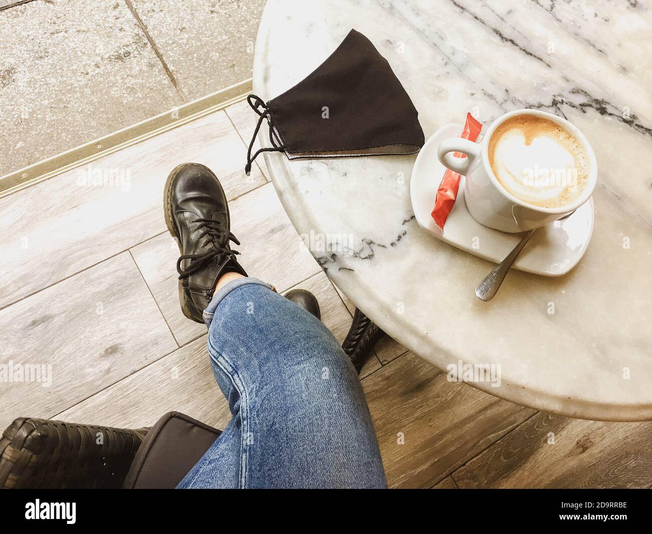 donna che ha un caffè in un bar con la maschera Foto Stock