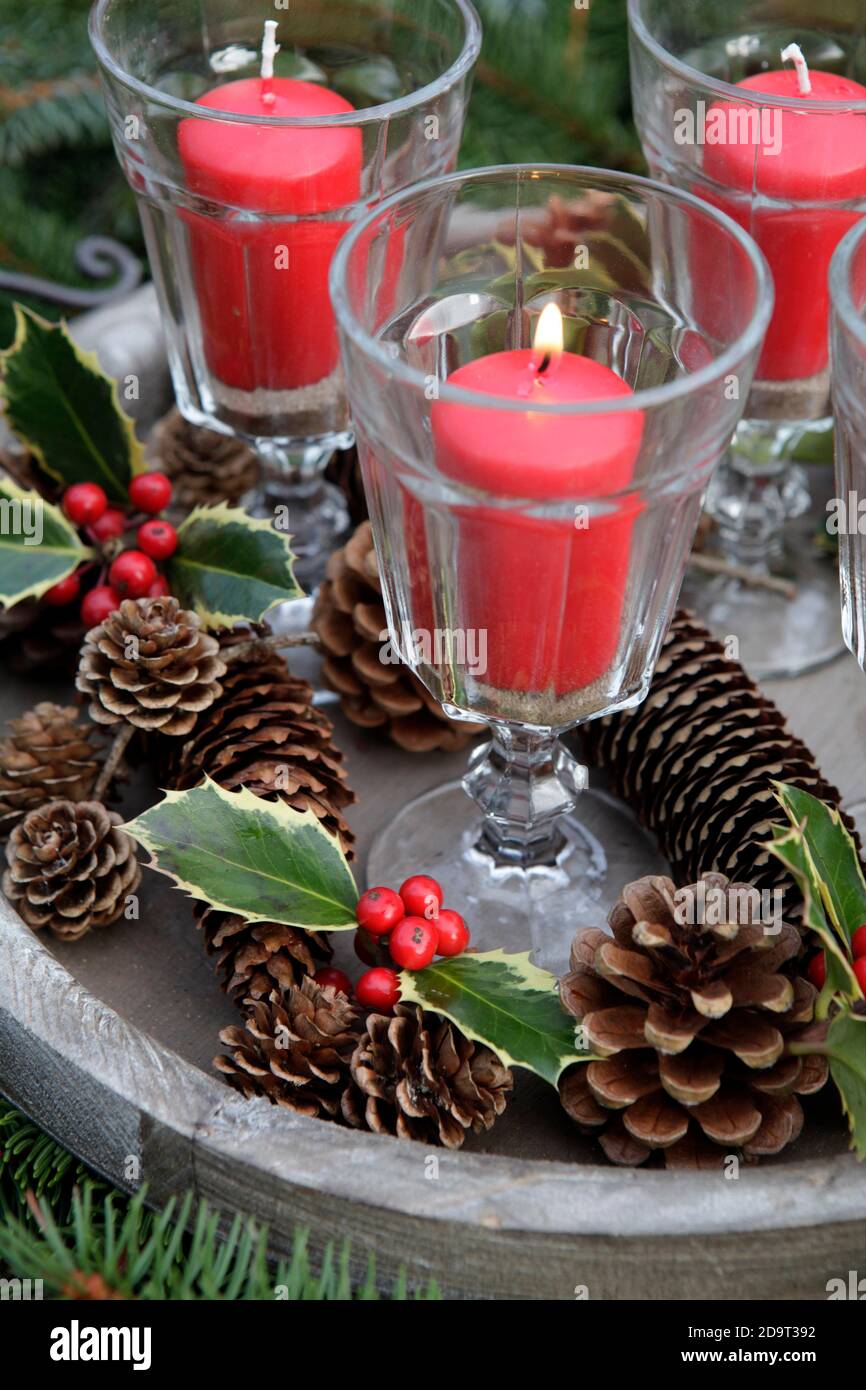 Candele rosse illuminate in bicchieri da vino in un'urna da giardino  Decorato con agrifoglio natalizio DISPONIBILE SOLO PER IL REGNO UNITO -  CONTATTARE L'UFFICIO Foto stock - Alamy