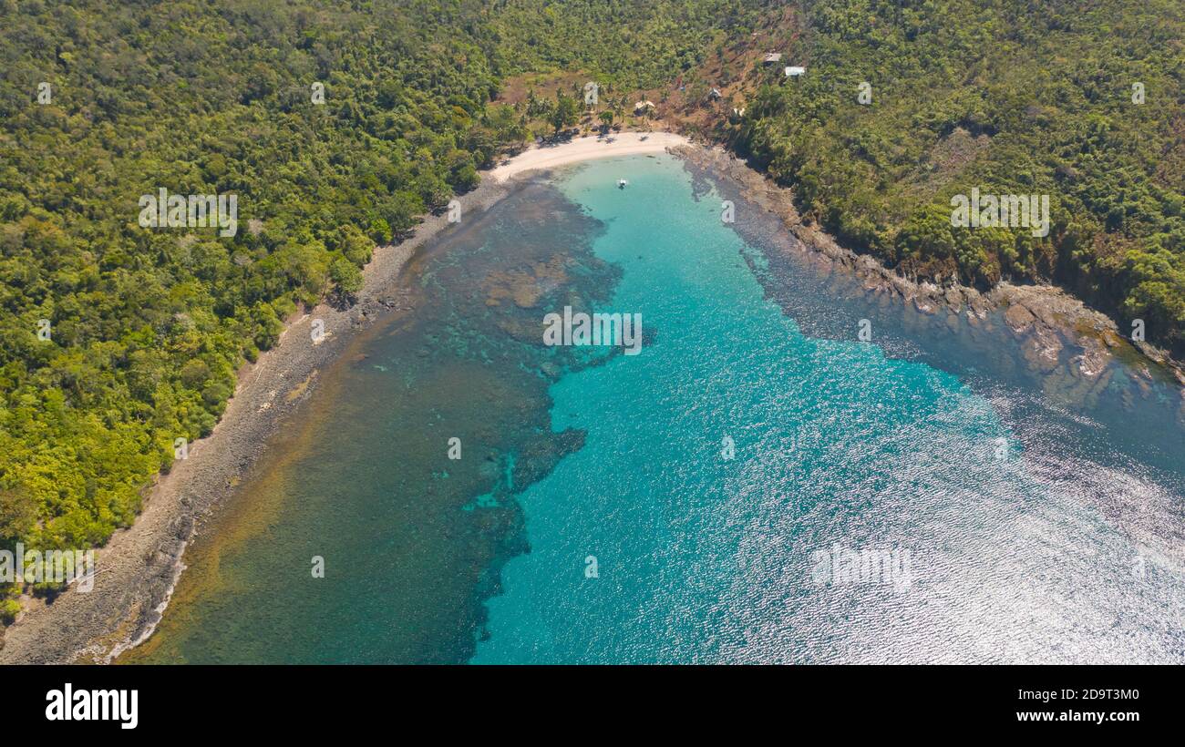 Baia Mare con acque turchesi e una piccola spiaggia bianca.Costa dell'isola di Camiguin, Filippine.bellissima laguna e l'isola vulcanica coperti di fitta foresta, vista dall'alto. Foto Stock