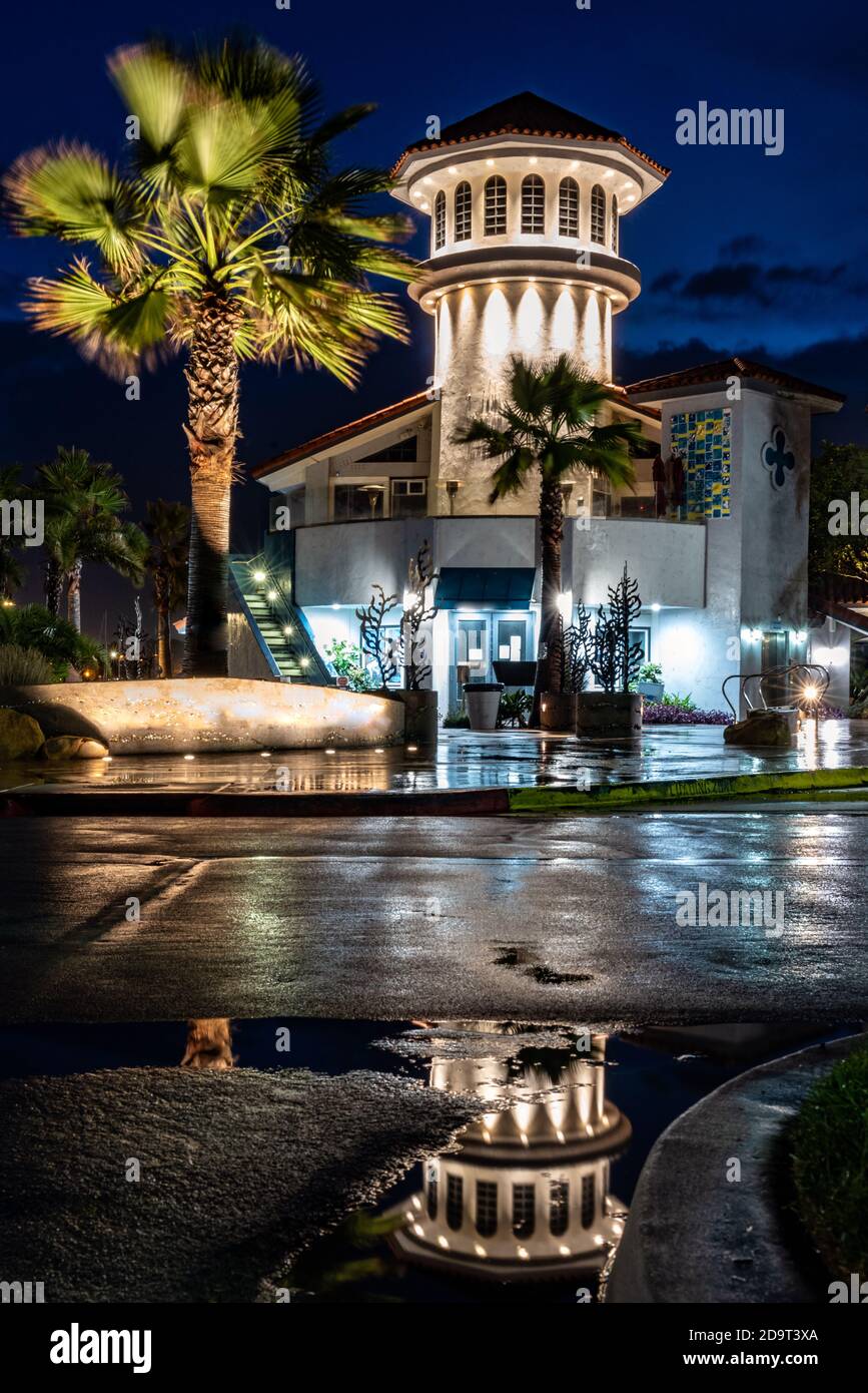 La torre a carosello del Ventura Harbour Village si riflette in una pozza d'acqua nel parcheggio luminoso e bagnato dalla pioggia mattutina. Foto Stock