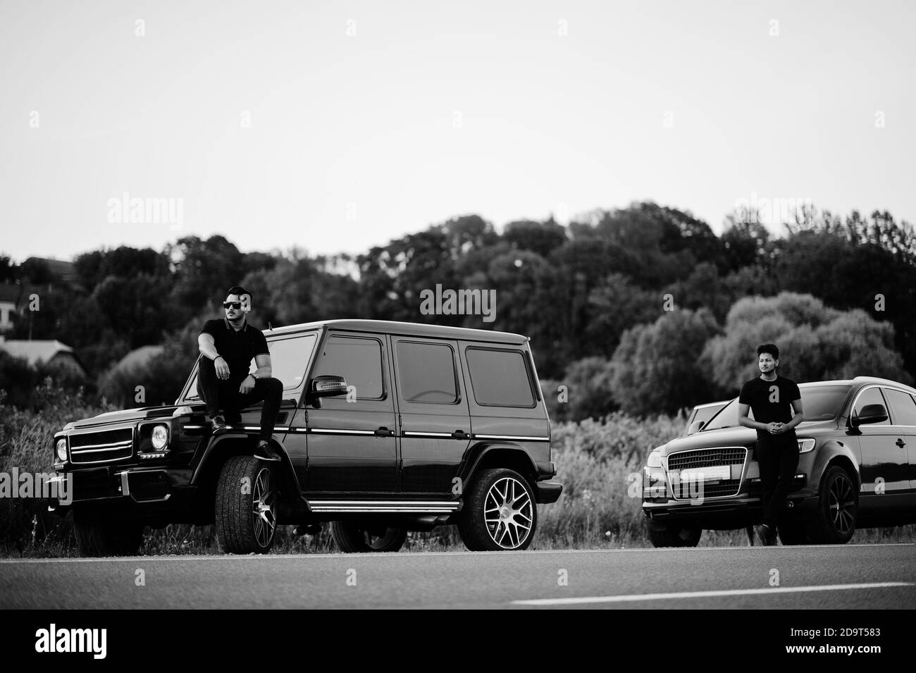 Due fratelli asiatici indossano su tutti i neri posati vicino alle auto suv. Foto Stock