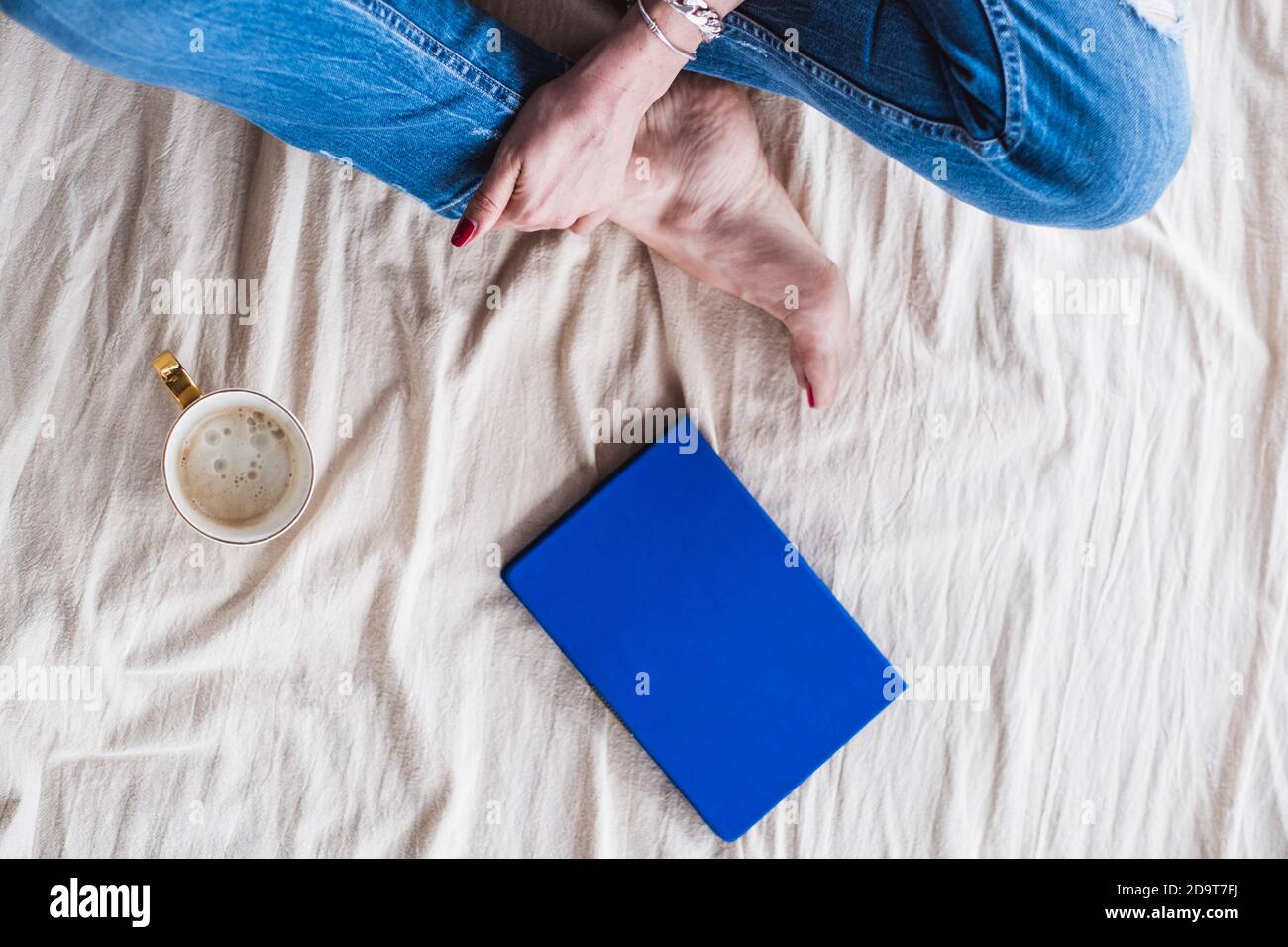 Ragazza seduta sul pavimento su una coperta con una tazza di caffè e un blocco note, vista dall'alto. La ragazza scrive le sue idee Foto Stock