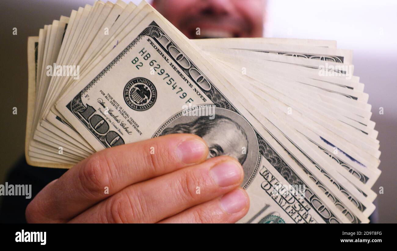 Un mucchio di 100 dollari fatture in un uomo ricco mani Foto Stock