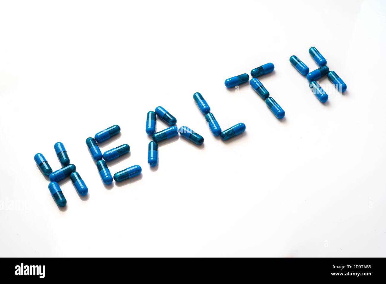 pillole blu che formano la parola salute su uno sfondo bianco, vista inclinata Foto Stock