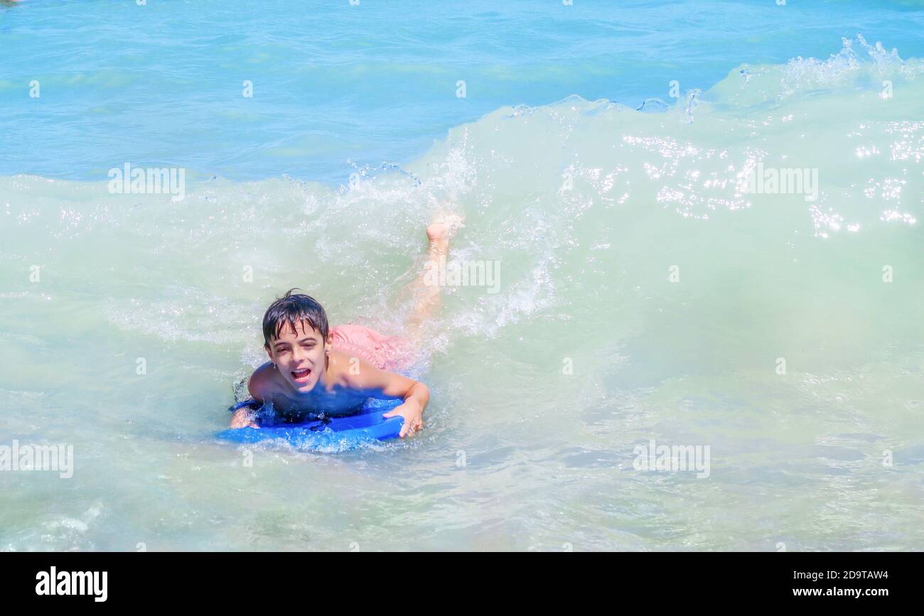 bodyboarding bambino in un mare blu con un'espressione di divertimento e felicità sul viso Foto Stock