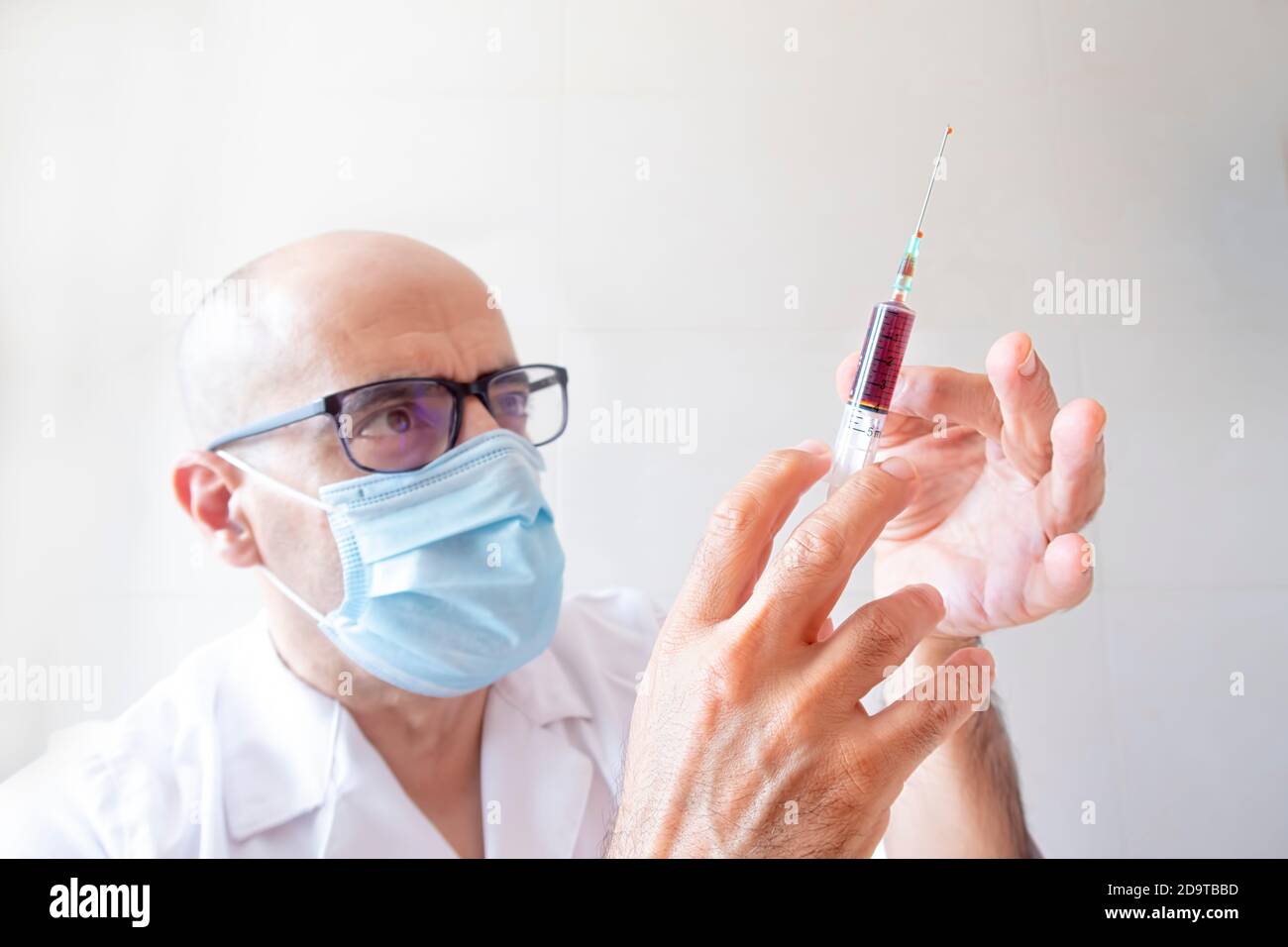 medico con una siringa di sangue che batte con la mano fuori aria Foto Stock