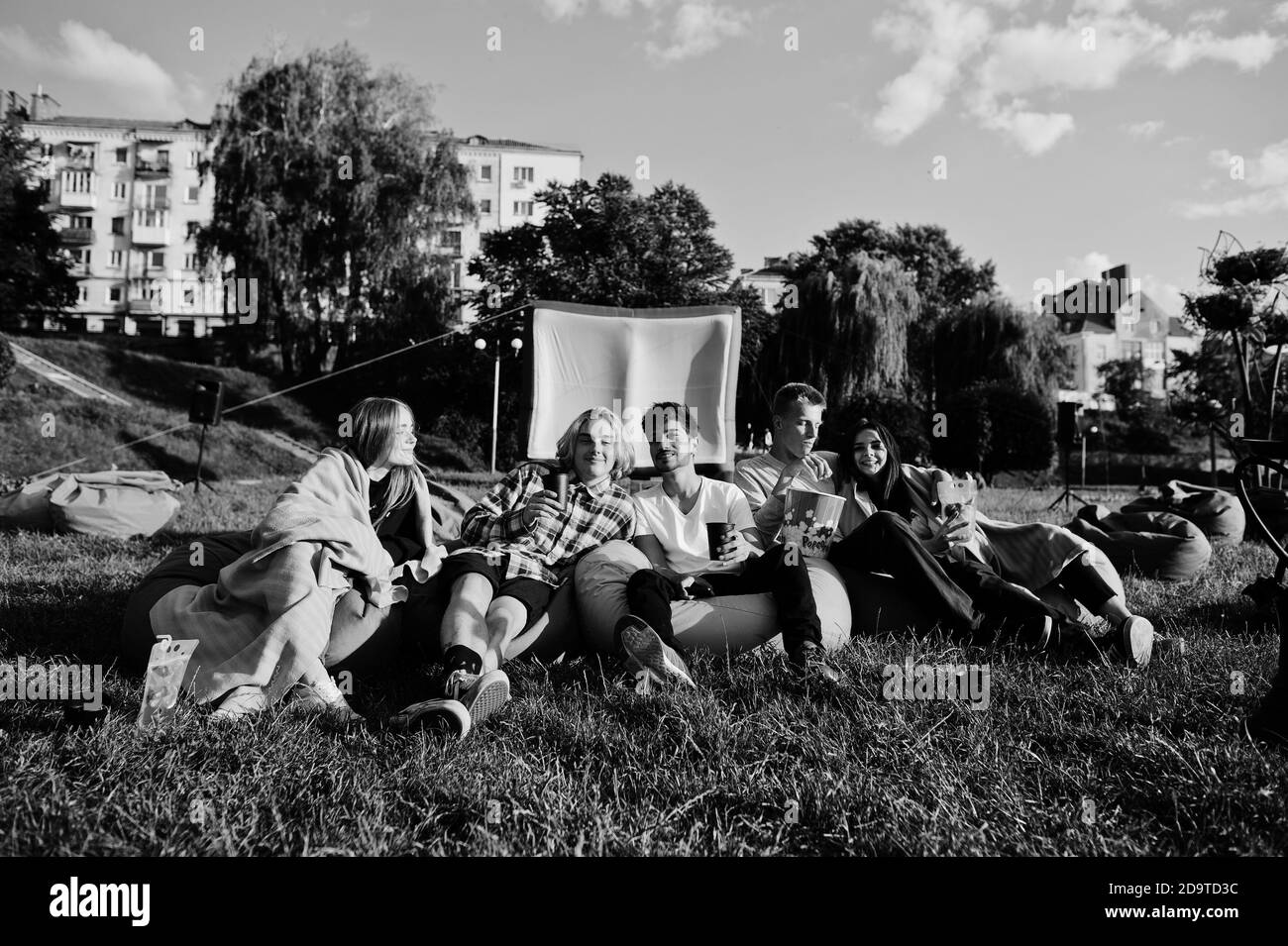 Gruppo giovane multietnico di persone che guardano film al poof nel cinema all'aperto. Foto Stock
