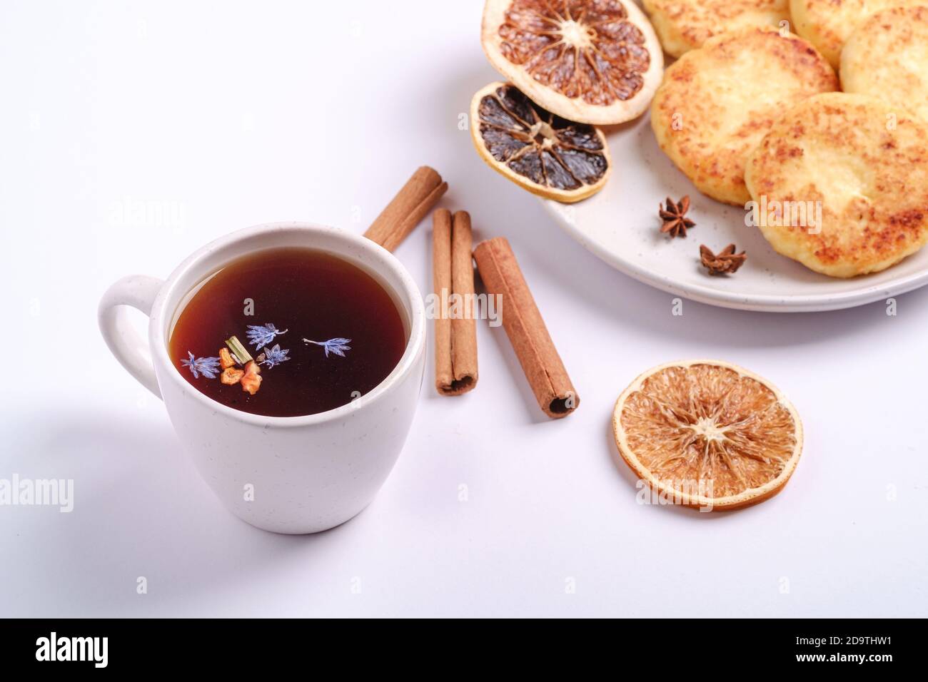 Frittelle di formaggio cottage con tè nero aromatico caldo, umore della prima colazione di Natale con anice e cannella su sfondo bianco, vista angolare Foto Stock