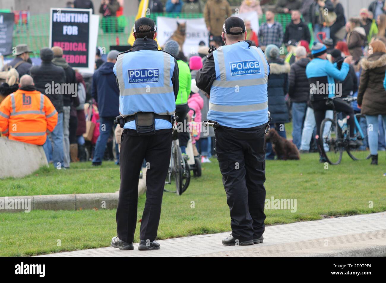 Due ufficiali di collegamento della polizia che osservano la folla dei manifestanti a. Una dimostrazione di blocco al di fuori del Parlamento scozzese Foto Stock