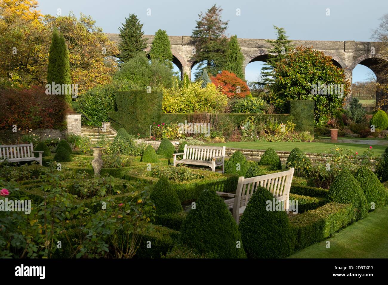 Kilver Court Gardens, panchina presso lo storico giardino sul lago di Shepton Mallet, Somerset UK, fotografata in autunno con foglie sugli alberi che girano colore Foto Stock