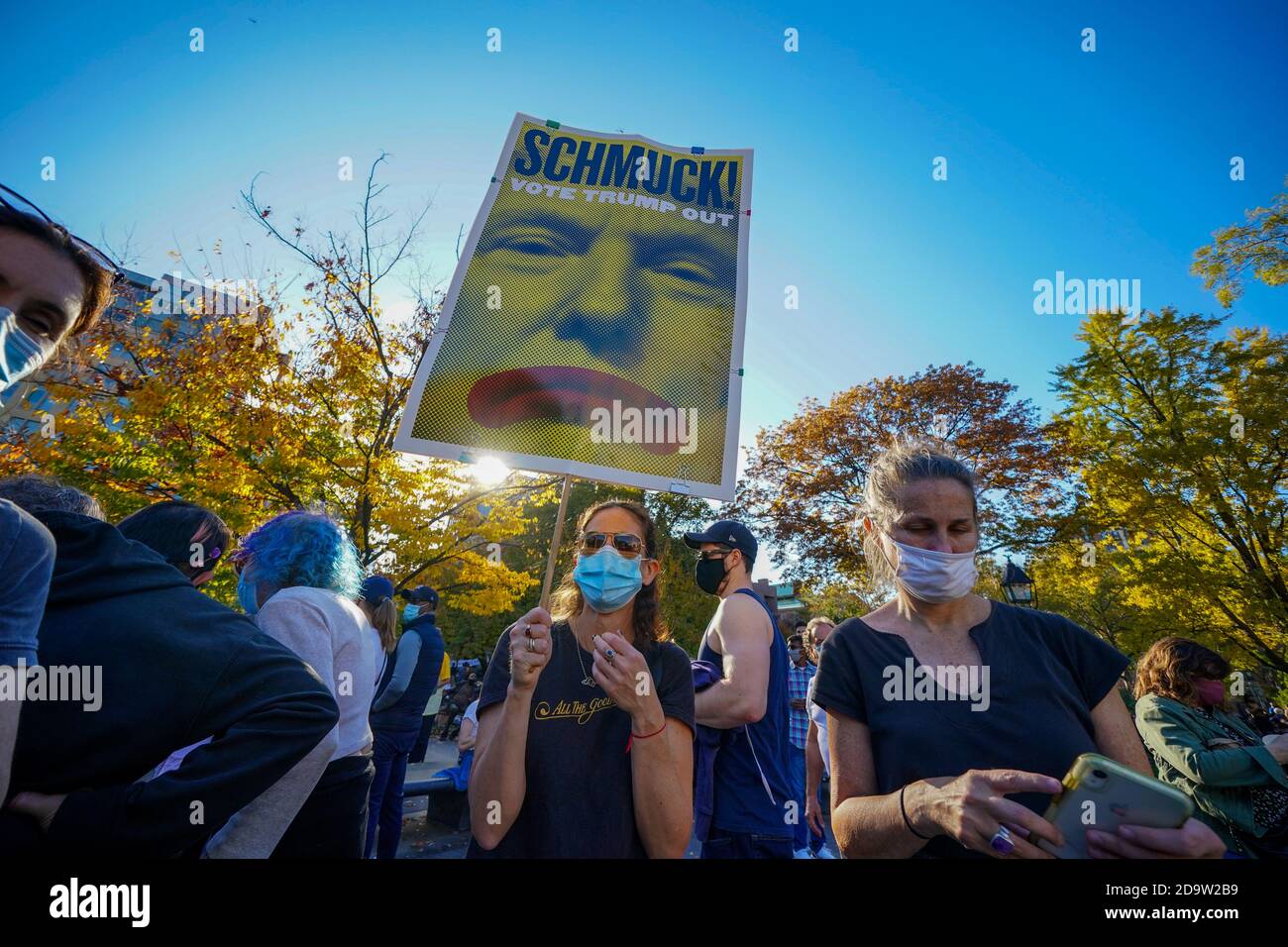 Una donna che indossa una maschera per il viso tiene un cartello che dice, Schmuck! Votate Trump mentre New York City erutta per celebrare la vittoria di Biden come 46° presidente degli Stati Uniti al Washington Square Park di New York. Foto Stock