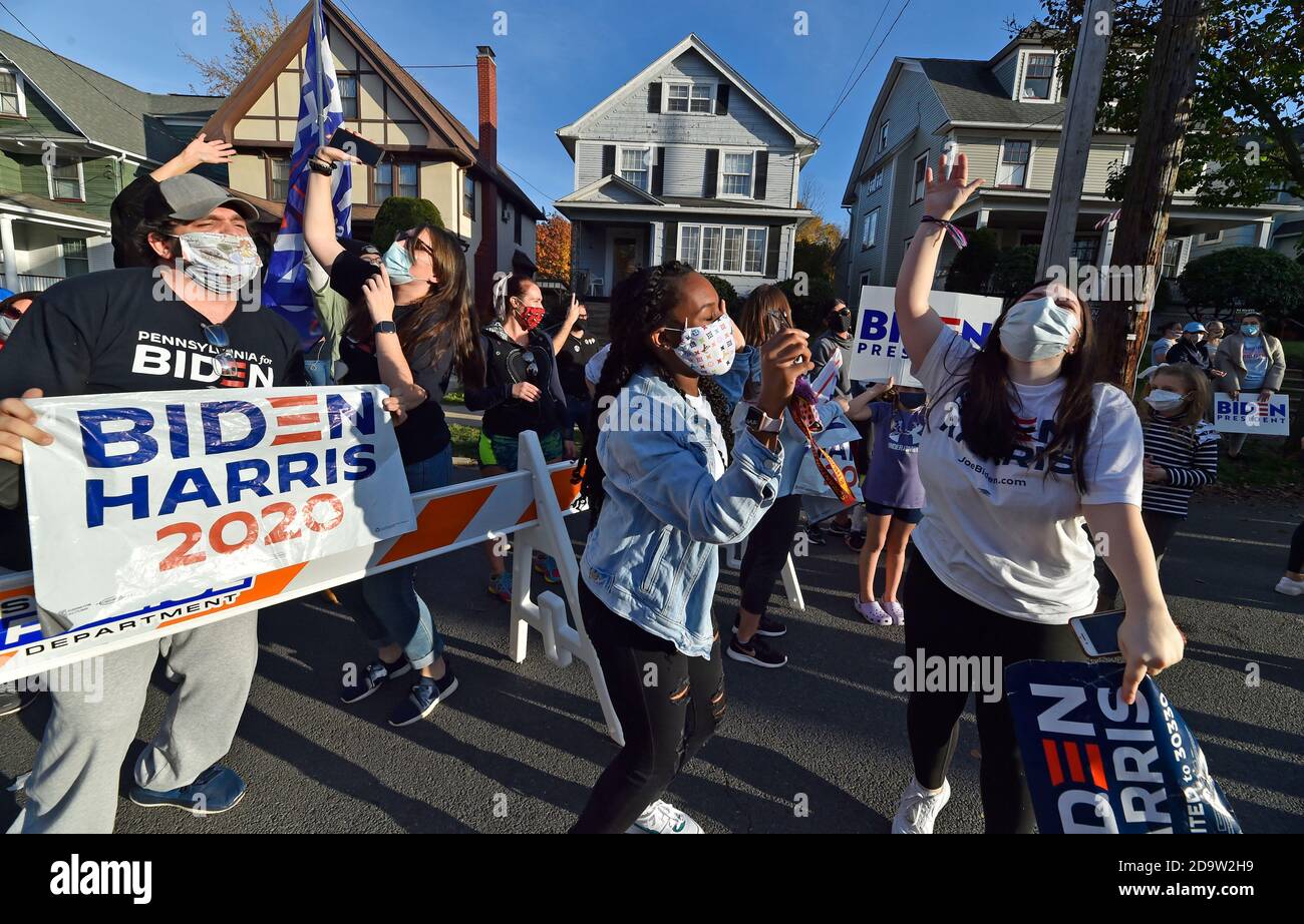 Le persone che indossano maschere celebrano l'elezione di Joe Biden al presidente fuori della sua casa d'infanzia a Scranton.Joe Biden è nato e cresciuto a Scranton, il lunedì ha visitato la sua casa d'infanzia e ha lasciato un messaggio sulla parete della camera di famiglia. I sostenitori sono venuti a casa a North Washington Street a Scranton dopo che Biden ha vinto le elezioni, un flusso costante di automobili che si guidano piangendo, salutando e ballando fuori casa sua. Foto Stock