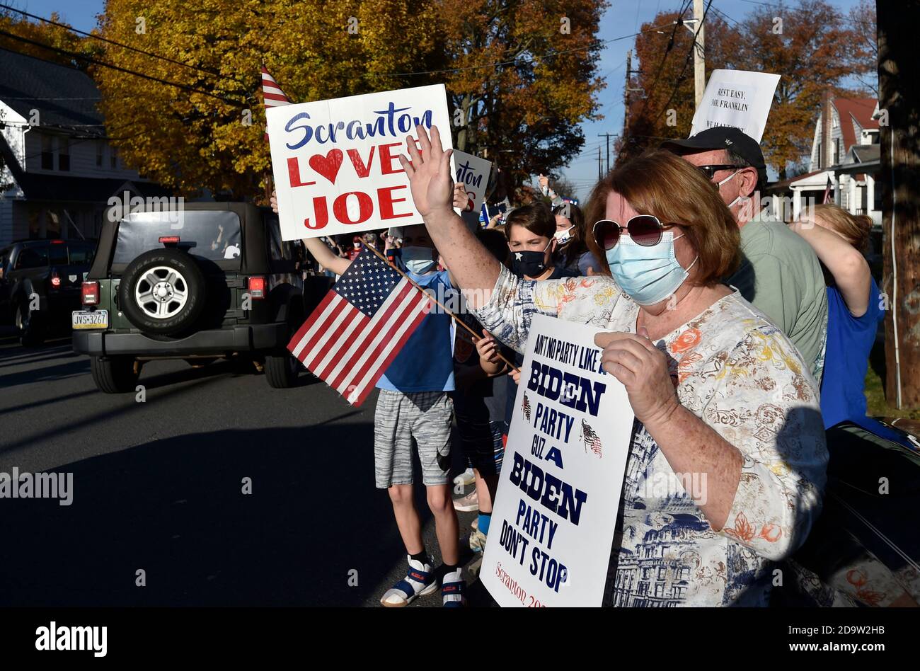 La gente che indossa la maschera mentre tiene i cartelli celebrano sulla via di North Washington in Scranton.Joe Biden è stato sopportato e cresciuto in Scranton, lui il lunedì ha visitato la sua casa d'infanzia e ha lasciato un messaggio sulla parete della stanza della famiglia. I sostenitori sono venuti a casa a North Washington Street a Scranton dopo che Biden ha vinto le elezioni, un flusso costante di automobili che si guidano piangendo, salutando e ballando fuori casa sua. Foto Stock