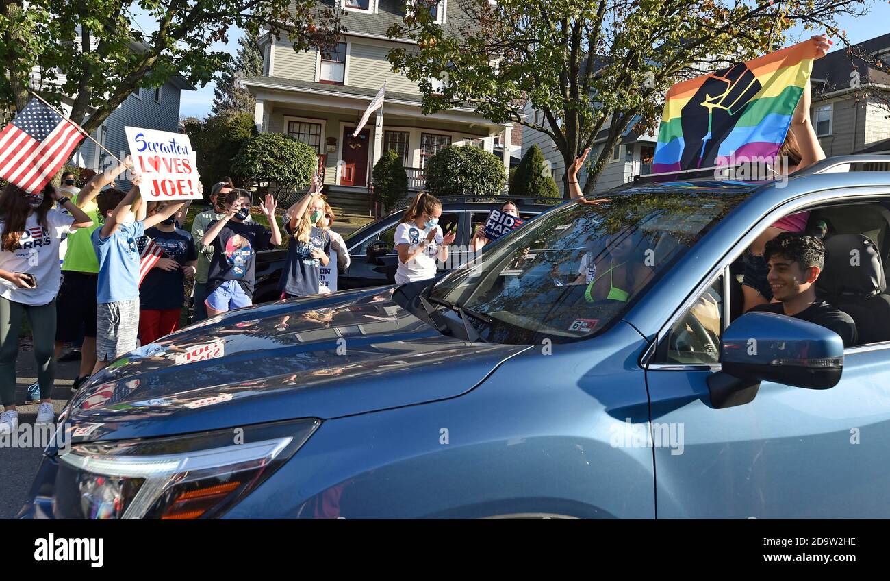 La gente che indossa la maschera mentre tiene i cartelli celebrano sulla via di North Washington in Scranton.Joe Biden è stato sopportato e cresciuto in Scranton, lui il lunedì ha visitato la sua casa d'infanzia e ha lasciato un messaggio sulla parete della stanza della famiglia. I sostenitori sono venuti a casa a North Washington Street a Scranton dopo che Biden ha vinto le elezioni, un flusso costante di automobili che si guidano piangendo, salutando e ballando fuori casa sua. Foto Stock