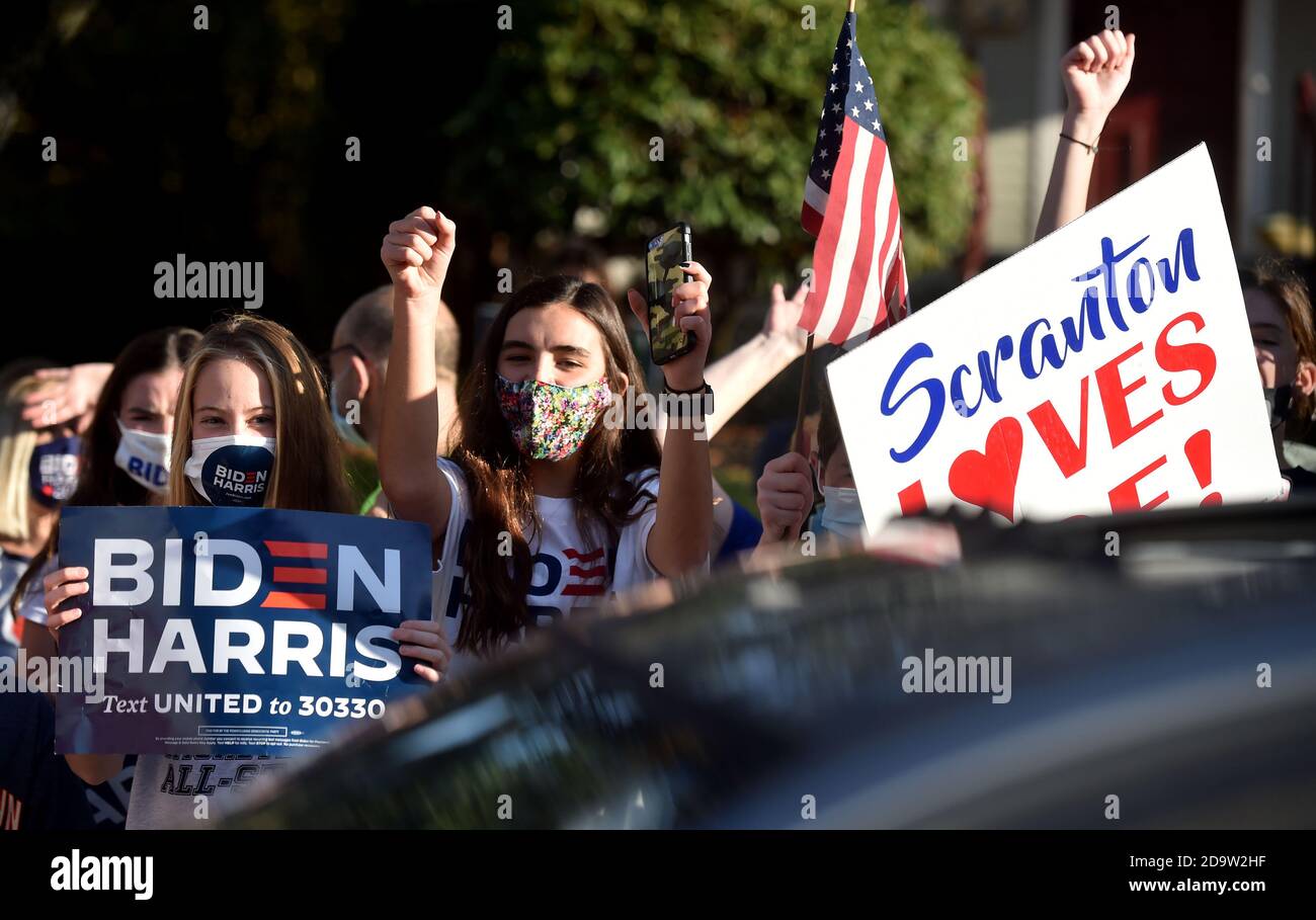 I bambini che indossano maschere celebrano l'elezione di Joe Biden al presidente fuori della sua casa d'infanzia a Scranton.Joe Biden è nato e cresciuto a Scranton, il lunedì ha visitato la sua casa d'infanzia e ha lasciato un messaggio sulla parete della camera di famiglia. I sostenitori sono venuti a casa a North Washington Street a Scranton dopo che Biden ha vinto le elezioni, un flusso costante di automobili che si guidano piangendo, salutando e ballando fuori casa sua. Foto Stock