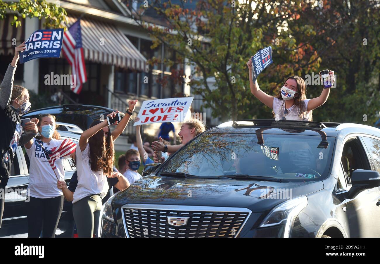 Le persone che indossano maschere celebrano l'elezione di Joe Biden al presidente fuori della sua casa d'infanzia a Scranton.Joe Biden è nato e cresciuto a Scranton, il lunedì ha visitato la sua casa d'infanzia e ha lasciato un messaggio sulla parete della camera di famiglia. I sostenitori sono venuti a casa a North Washington Street a Scranton dopo che Biden ha vinto le elezioni, un flusso costante di automobili che si guidano piangendo, salutando e ballando fuori casa sua. Foto Stock