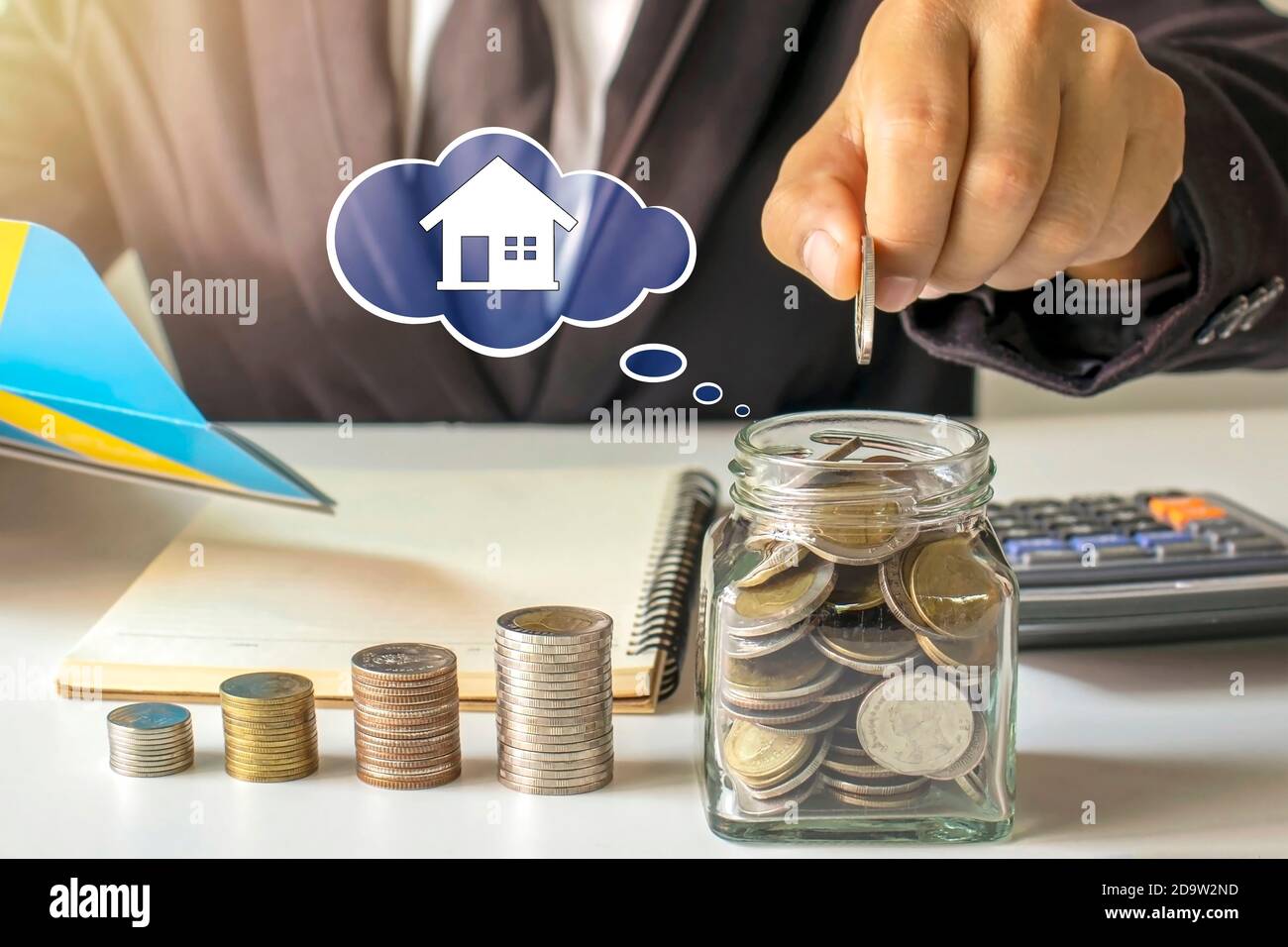 Uomo d'affari che mette i soldi in un vaso di risparmio, idea di risparmio di denaro per comprare una casa. Foto Stock