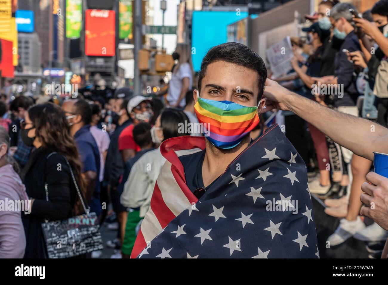 New York, Stati Uniti. 07 novembre 2020. Un sostenitore drappeggiato con bandiere celebra la vittoria dell'elezione del biglietto di Biden/Harris a Times Square. La gente è scese in strada in massa dopo che molti dei principali media hanno chiamato l'elezione per l'ex vice presidente Joe Biden. Rapporto NYPD ci è una gamma di 500 - 900 persone radunate in Times Square. Gruppi simili si sono riuniti nelle strade della città e in tutto il paese. Credit: SOPA Images Limited/Alamy Live News Foto Stock