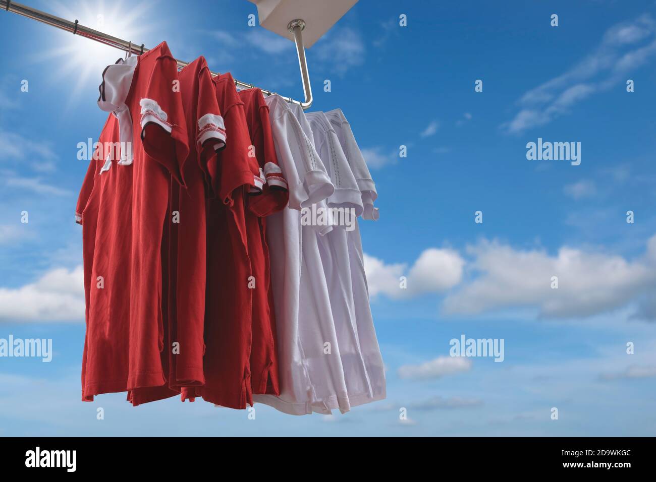 T-shirt rosse e bianche appese su un guardaroba con fondo blu. Foto Stock