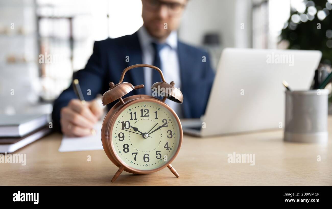 Focus su orologio con occupato giovane uomo d'affari in background. Foto Stock