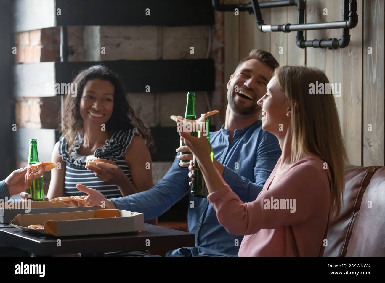 Amici felici e diversi trascorrono il fine settimana insieme gustando birra e pizza Foto Stock