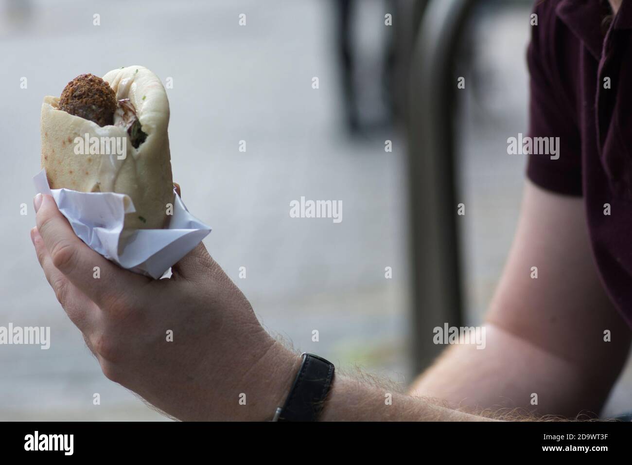 Uomo che tiene un pane di Pita con Falafel, un tipico cibo medio orientale, palline fritte profonde fatte di ceci macinati. Tel Aviv, Israele Foto Stock