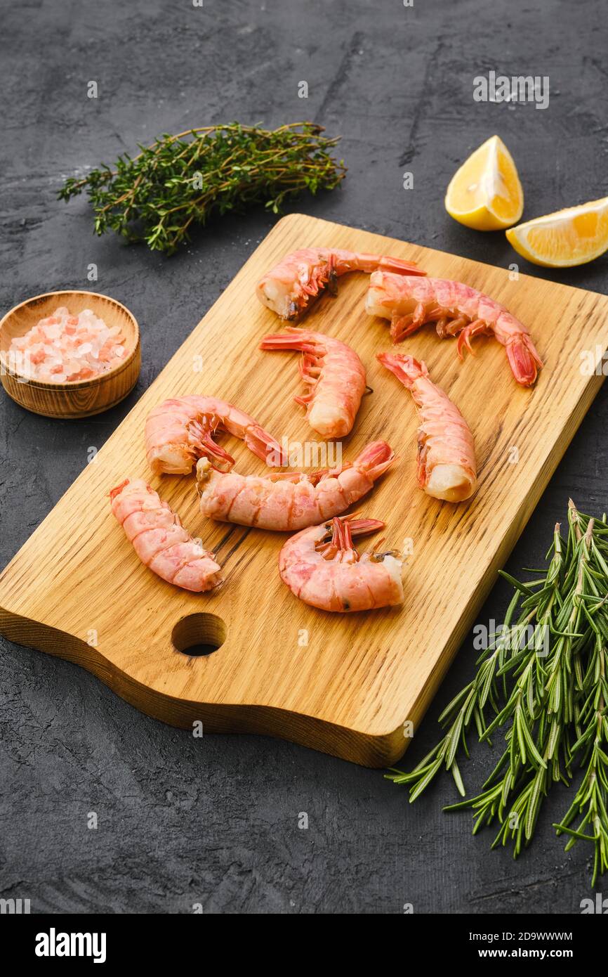 Code di gamberetti surgelate surgelate su tagliere di legno Foto Stock