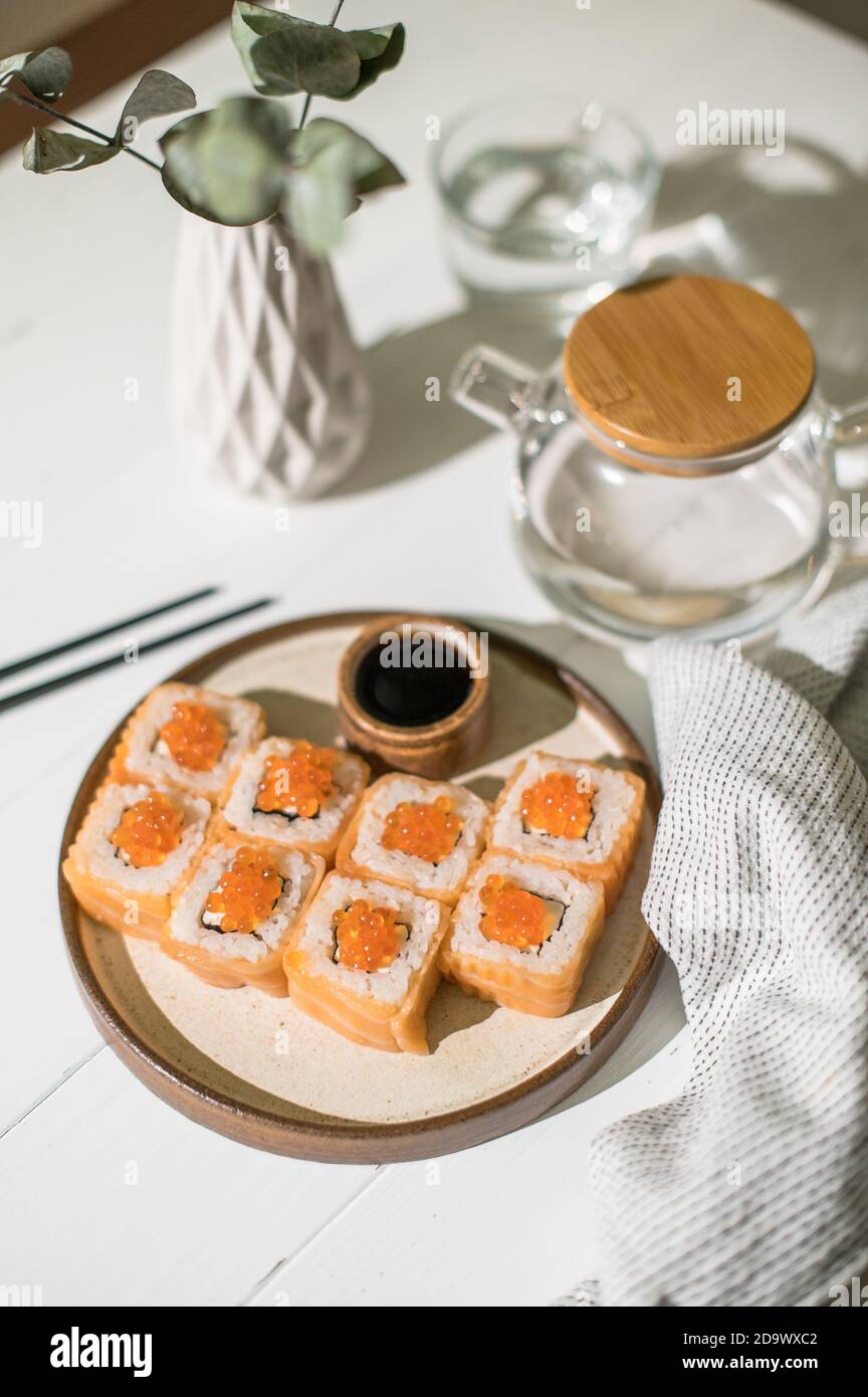 Sushi roll con salmone e caviale. Cibo giapponese. Involtini di salmone e caviale serviti su sfondo di legno bianco Foto Stock