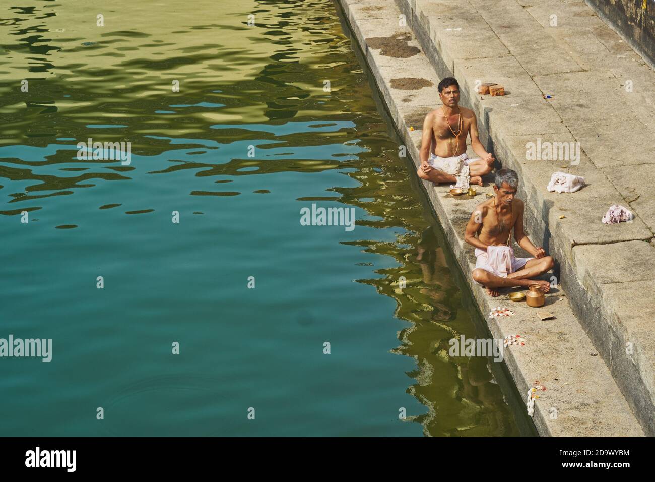 Due sacerdoti Brahmin meditano dal serbatoio d'acqua nei terreni di Udupi Sri Krishna Matha o Balkrishna Tempio a Udipi (Udupi), Karnataka, India del Sud Foto Stock