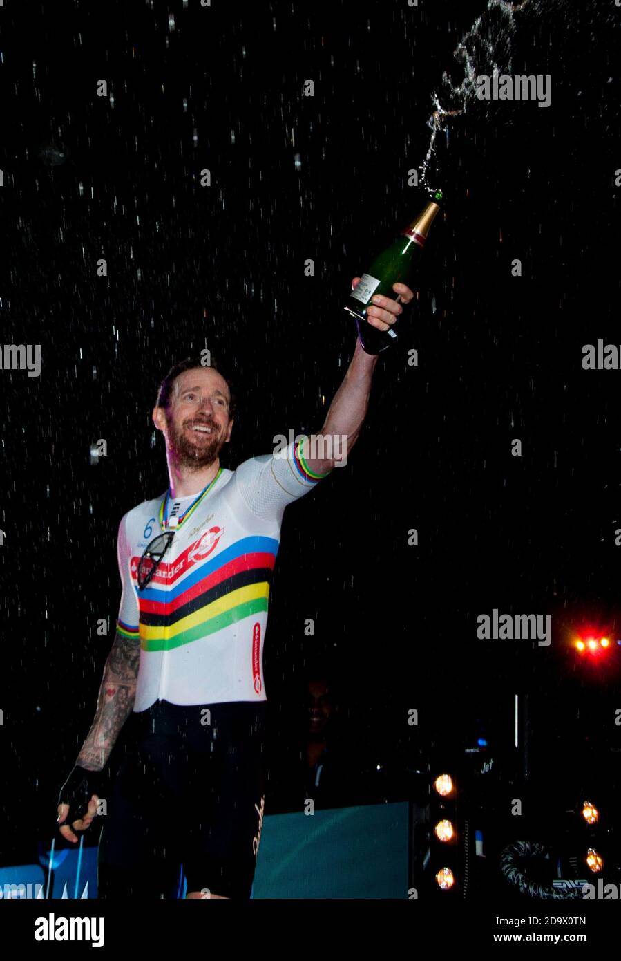 Bradley Wiggins lancia champagne alla folla mentre festeggia il traguardo sul podio. I piloti hanno partecipato al campionato di ciclismo di sei giorni a Lee Valley Velodrome, Londra, Regno Unito. Foto Stock