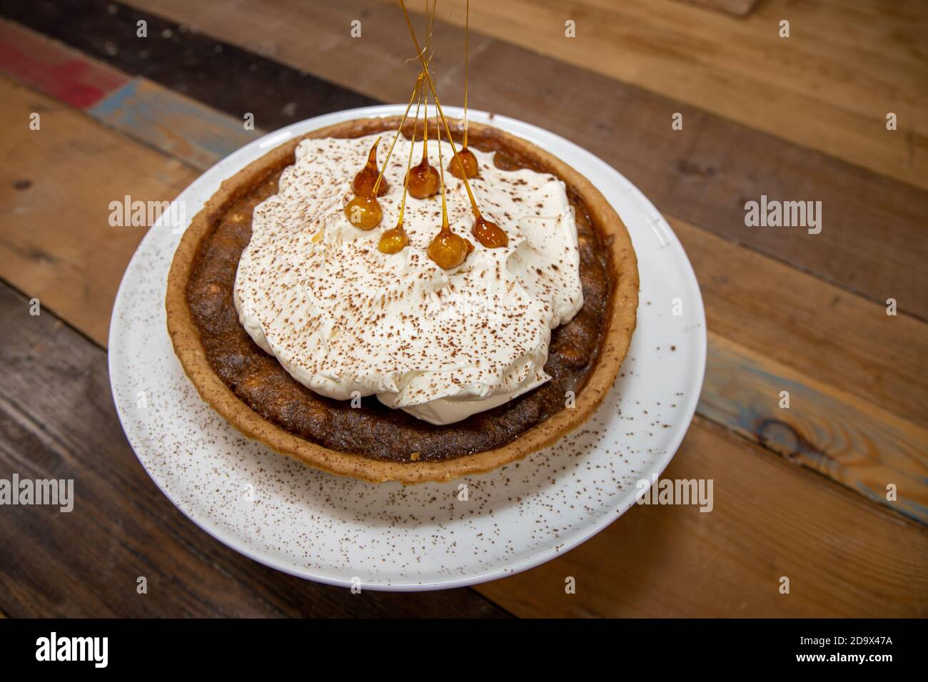 Una deliziosa torta del deserto di una Toffee Bonfire e nocciola crostata su un piano di lavoro di cucina in legno Foto Stock