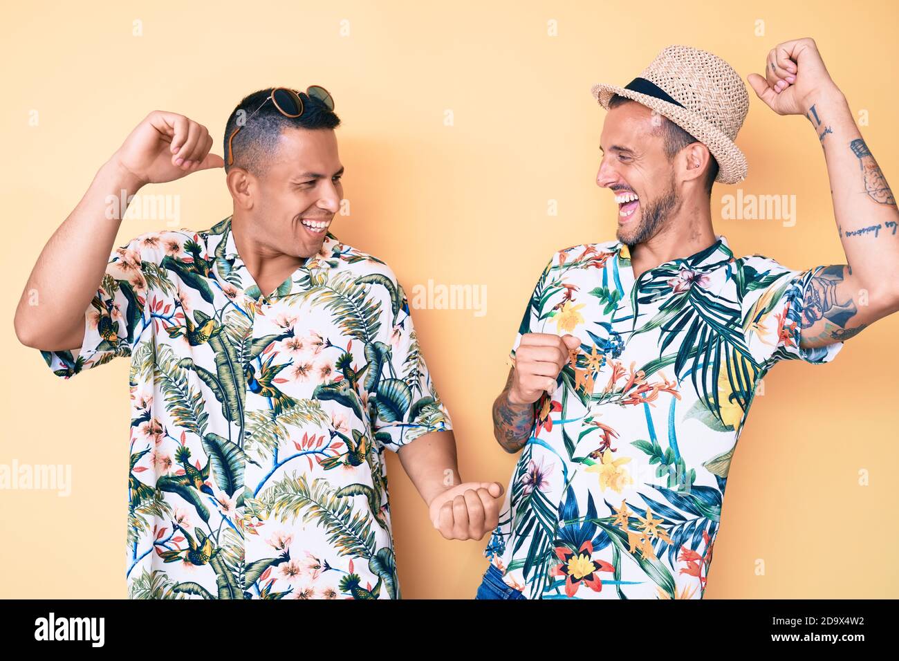Giovane coppia gay di due uomini con cappello estivo e camicia hawaiana che  danzano allegro e allegro, sorridente casual e fiducioso ascolto di musica  Foto stock - Alamy