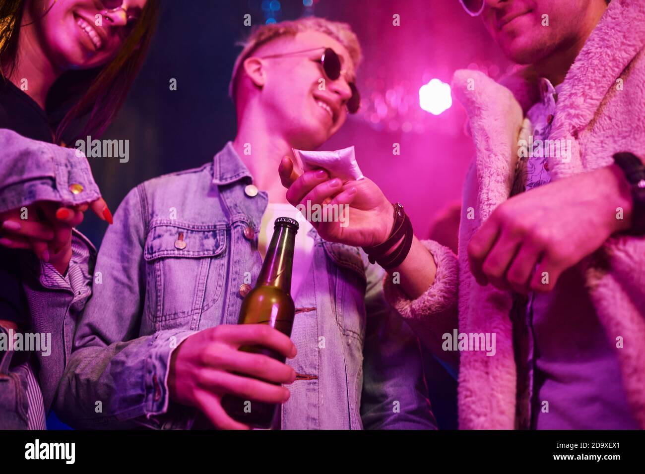 Acquisto di droghe. I giovani si divertono nel night club con luci laser colorate Foto Stock