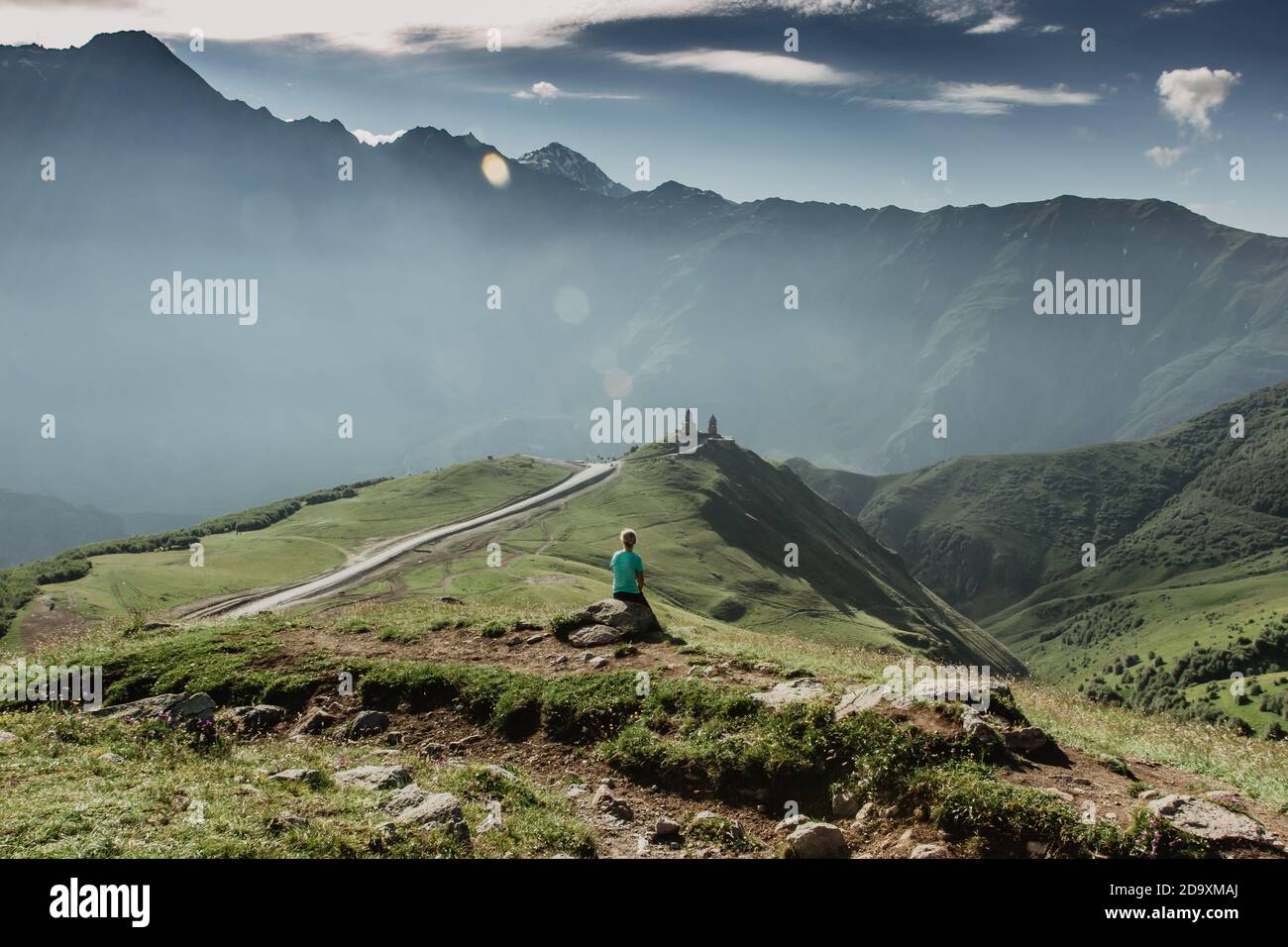 Giovane ragazza seduta e godendo di vedute della vetta del Caucaso, Georgia. Ragazza in montagna. Escursioni nella natura. Attivo sano lifestyle.Panorama Foto Stock