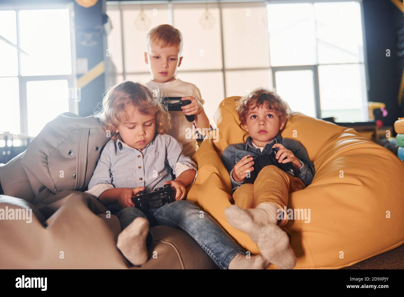 Bambini in abiti casual seduti insieme con il controller e giocare videogiochi Foto Stock