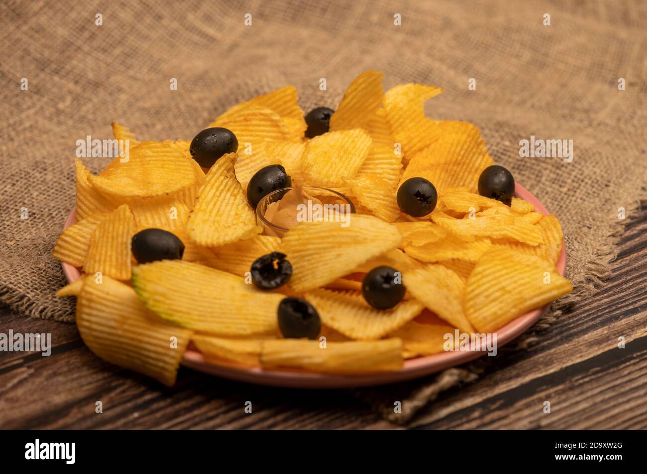Patatine croccanti e deliziose con salsa di senape e olive su un panno di casa grossolano. Primo piano Foto Stock