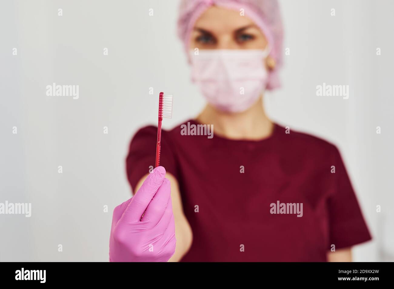 Giovane dentista femminile in piedi uniforme in ufficio di stomatologia e. spazzola di fissaggio Foto Stock
