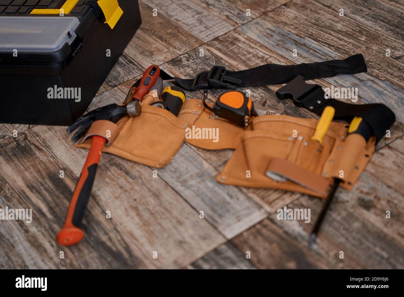 Cinghia con attrezzi di riparazione poggiati sul pavimento Foto Stock
