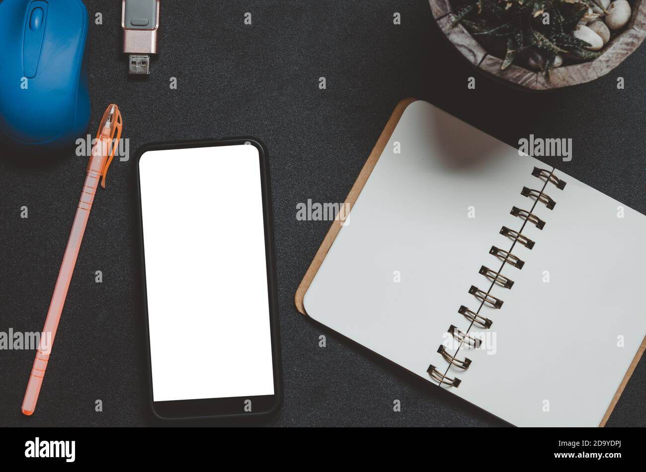 Guarda lo smart phone con mouse, penna e notebook su sfondo nero. Foto Stock
