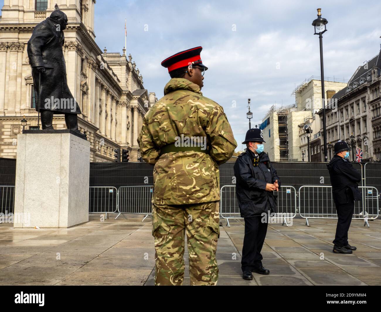 Poliziotto in maschere di fronte a una statua di Churchill in Piazza del Parlamento di Londra sulla memoria Domenica mattina. Foto Stock