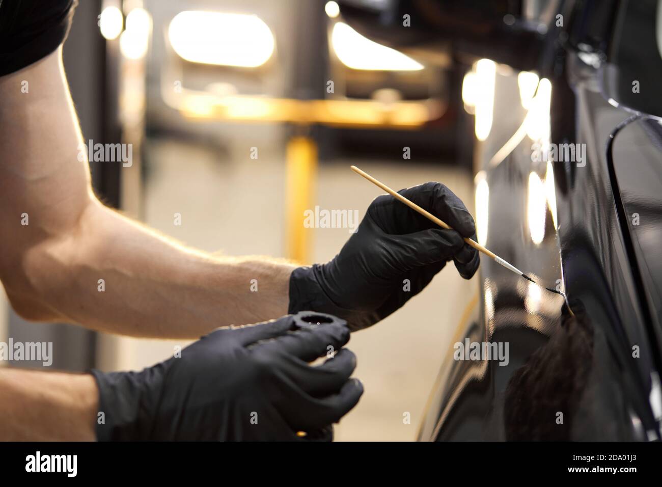 le mani dell'uomo usano la spazzola di dettaglio per verniciare l'auto o per pulire e rimuovere lo sporco, i dettagli dell'auto e il concetto di verniciatura per autolavaggio. primo piano Foto Stock