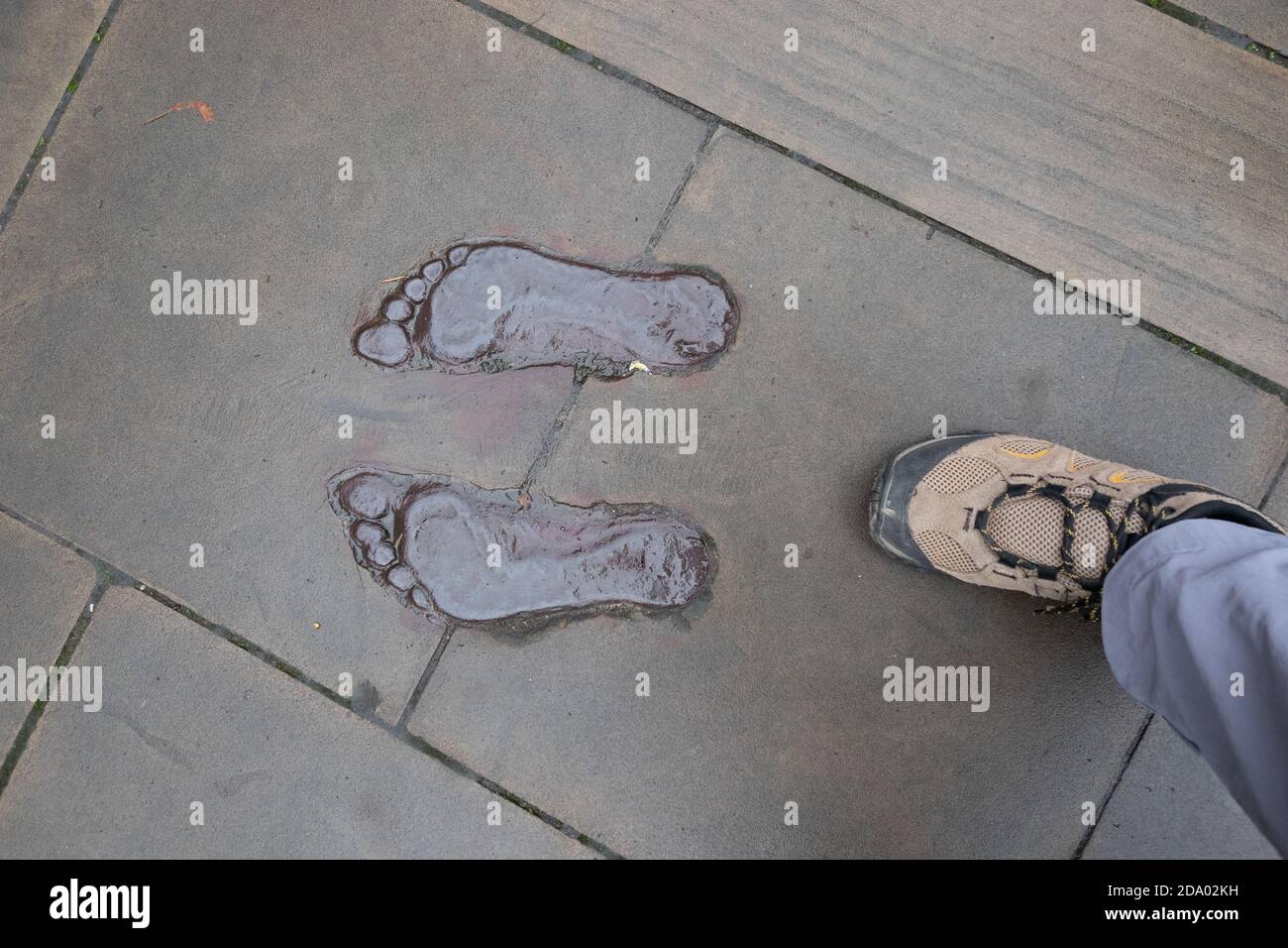 footprint nudi racchiuso in pavimentazione con un piede di appoggio accanto Foto Stock footprint nudi racchiuso in pavimentazione con un piede di appoggio accanto Foto Stock