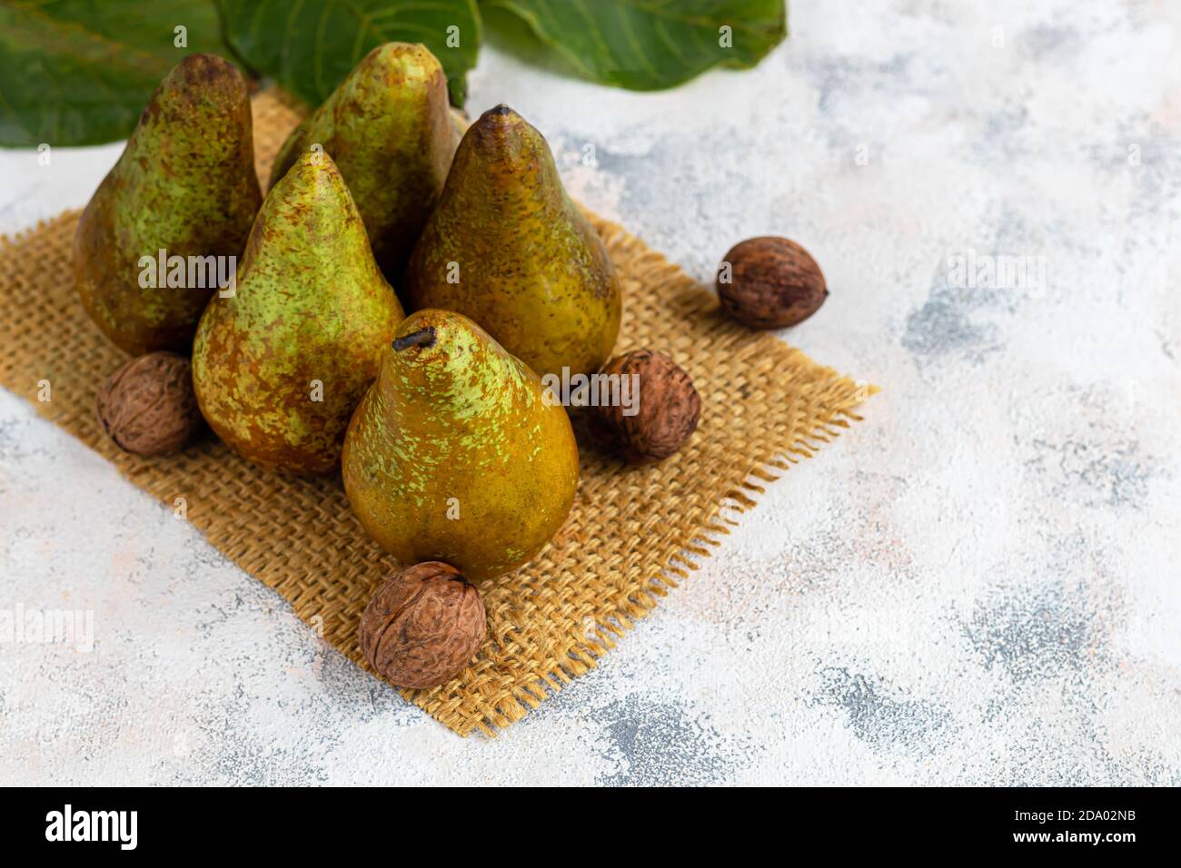 Pere su uno sfondo chiaro. Concetto autunnale. Nelle vicinanze si trovano patatine e noci di pera secca. Spazio di copia. Foto Stock