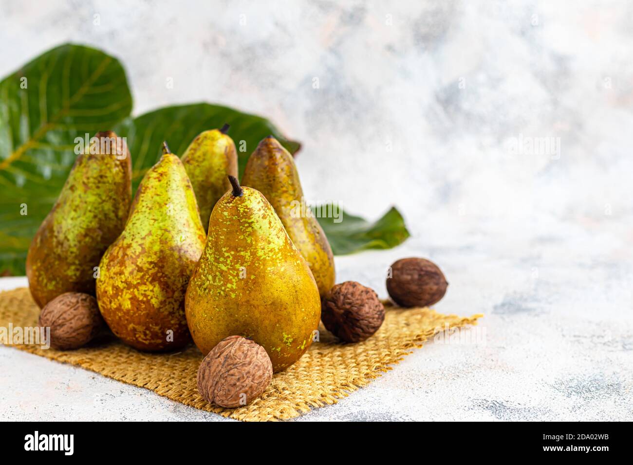 Pere su uno sfondo chiaro. Concetto autunnale. Nelle vicinanze si trovano patatine e noci di pera secca. Spazio di copia. Foto Stock