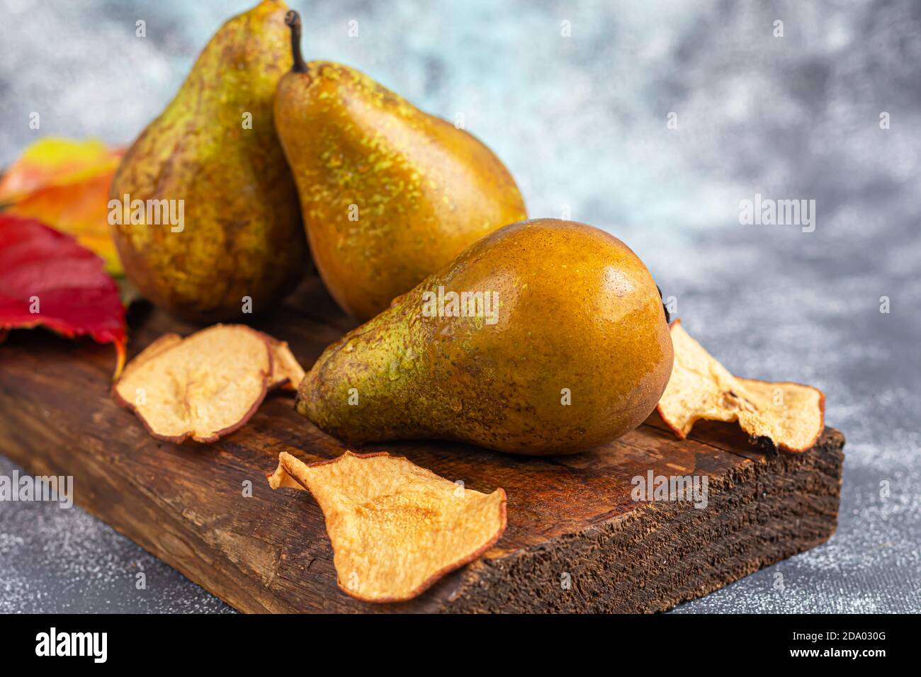 Pere su uno sfondo chiaro. Concetto autunnale. Nelle vicinanze si trovano patatine e noci di pera secca. Spazio di copia. Foto Stock